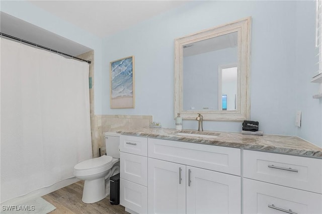 bathroom with vanity, toilet, wood-type flooring, and tile walls