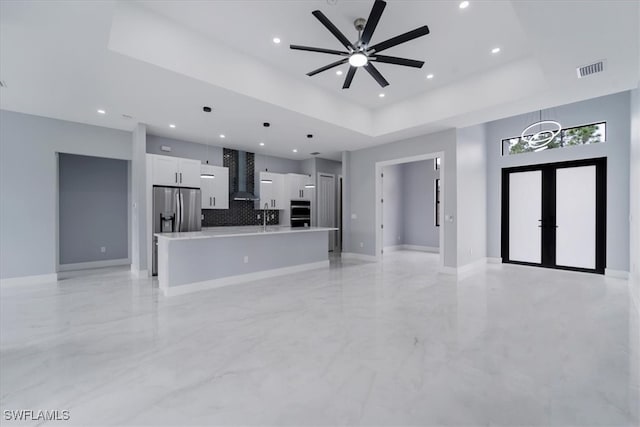 unfurnished living room with french doors, a tray ceiling, ceiling fan, and sink