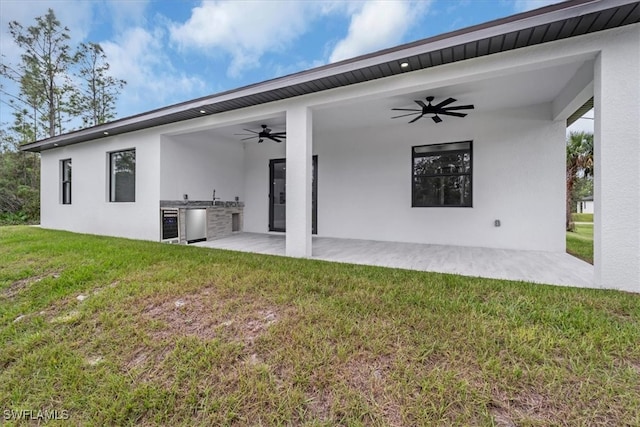 back of house with ceiling fan, area for grilling, a yard, and a patio