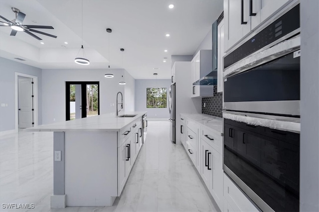 kitchen with a center island with sink, white cabinets, sink, and appliances with stainless steel finishes