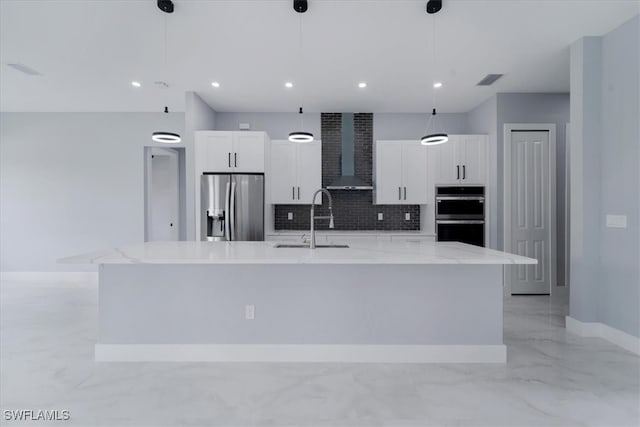 kitchen with a large island with sink, wall chimney exhaust hood, decorative light fixtures, and appliances with stainless steel finishes