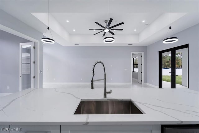 kitchen with light stone countertops, decorative light fixtures, and sink