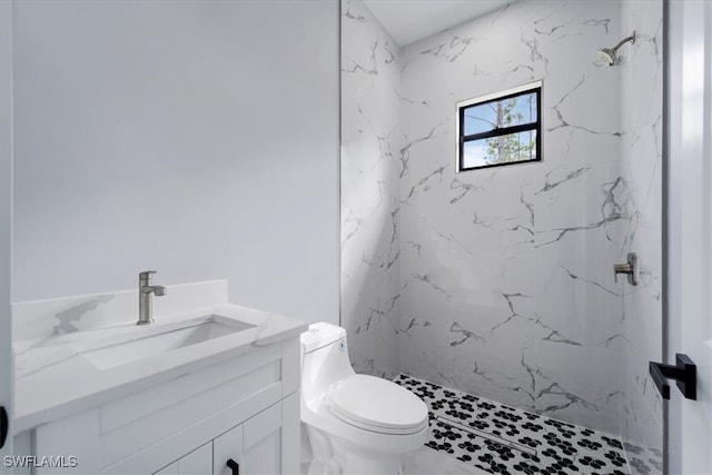 bathroom with a tile shower, vanity, and toilet