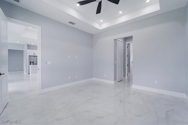 empty room with a tray ceiling and ceiling fan