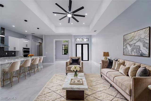 living room with ceiling fan and a tray ceiling