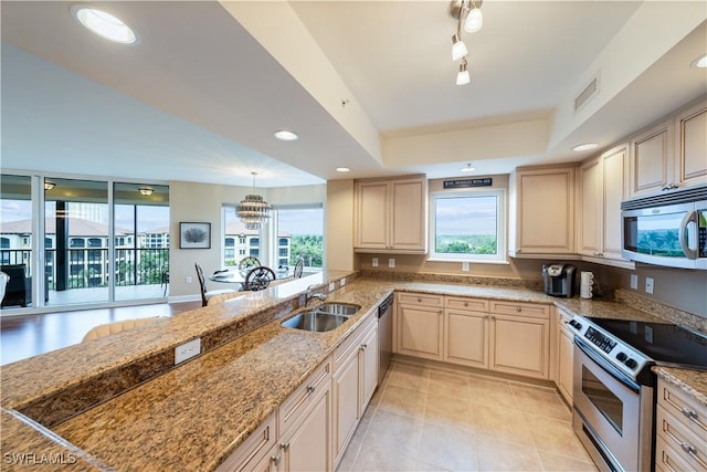 23540 Via Veneto Blvd Unit 605, Estero, FL 34134 - kitchen featuring stainless steel appliances, a sink, light tile patterned floors, light stone counters, and a tray ceiling