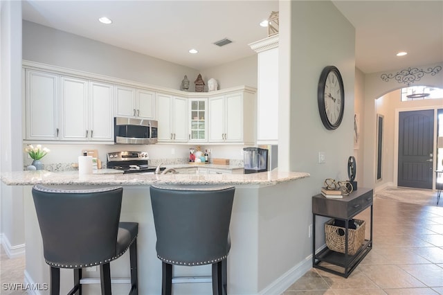 kitchen featuring white cabinetry, light stone counters, kitchen peninsula, and stainless steel appliances