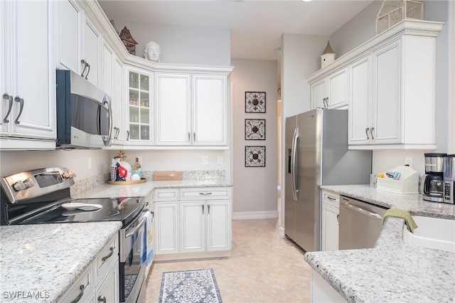 kitchen featuring white cabinets, appliances with stainless steel finishes, light tile patterned floors, and light stone counters