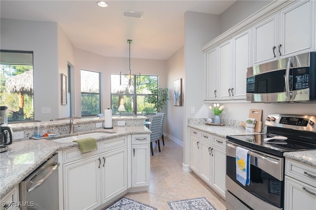 kitchen with white cabinetry, sink, light stone counters, pendant lighting, and appliances with stainless steel finishes