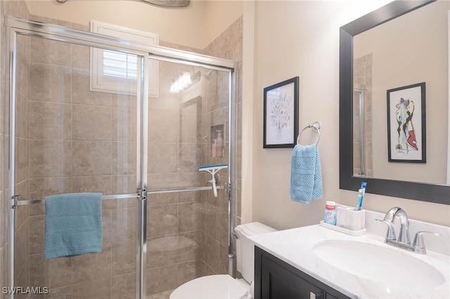 bathroom featuring vanity, toilet, and a shower with shower door