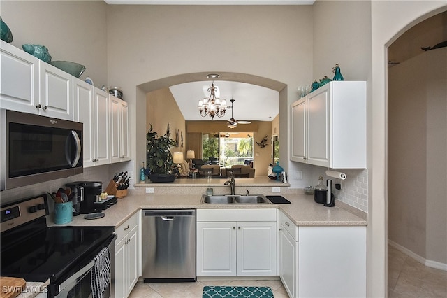 kitchen featuring decorative light fixtures, sink, white cabinets, light tile patterned floors, and stainless steel appliances