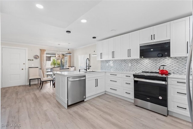 kitchen featuring white cabinets, sink, appliances with stainless steel finishes, decorative light fixtures, and kitchen peninsula