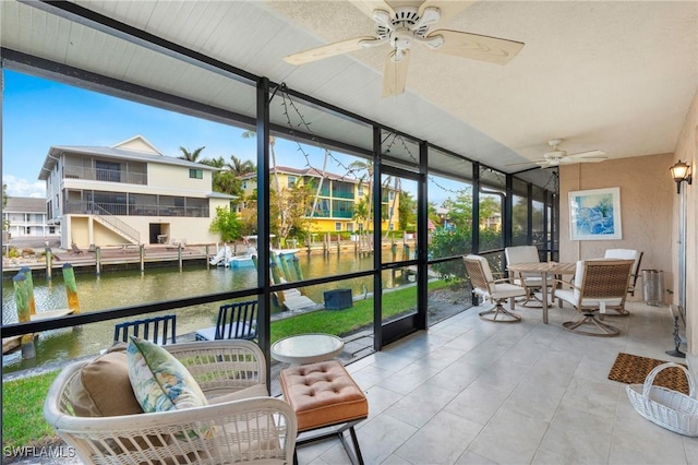 sunroom featuring ceiling fan, plenty of natural light, and a water view