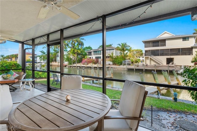 sunroom / solarium featuring ceiling fan and a water view