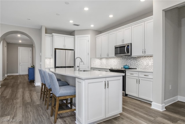 kitchen featuring white cabinets, sink, stainless steel appliances, and a kitchen island with sink