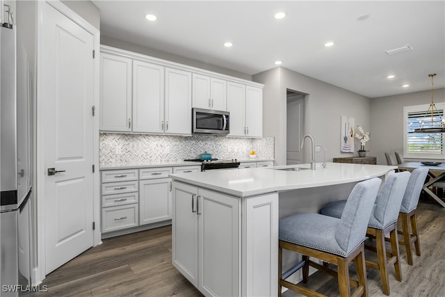 kitchen with sink, dark hardwood / wood-style floors, an island with sink, appliances with stainless steel finishes, and white cabinetry