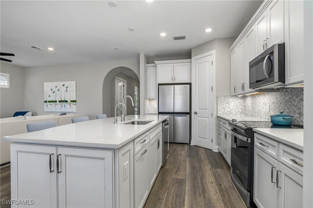 kitchen with sink, an island with sink, appliances with stainless steel finishes, dark hardwood / wood-style flooring, and white cabinetry