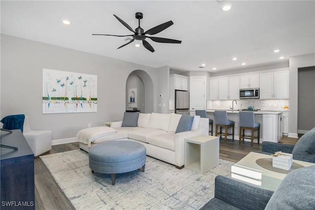 living area featuring light wood finished floors, arched walkways, baseboards, ceiling fan, and recessed lighting