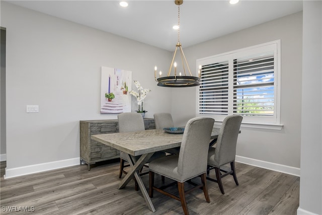 dining area with dark wood-type flooring and an inviting chandelier