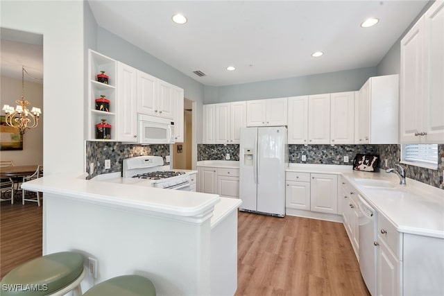 kitchen with white cabinetry, sink, kitchen peninsula, decorative light fixtures, and white appliances