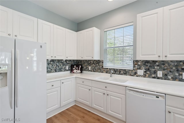 kitchen with white cabinetry, sink, light hardwood / wood-style floors, and white appliances