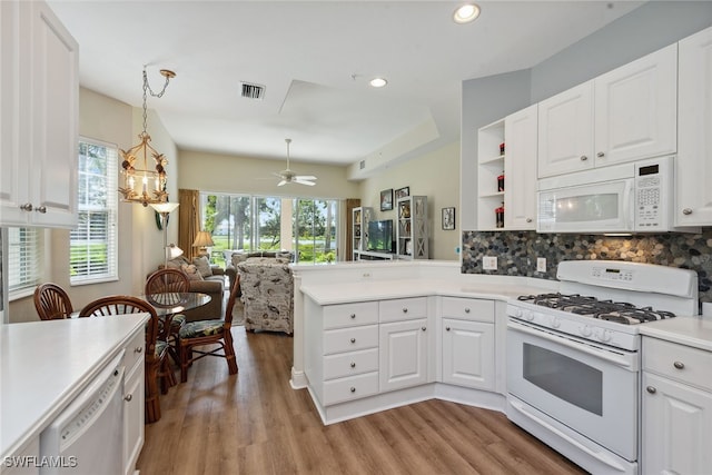 kitchen with white cabinetry, hanging light fixtures, kitchen peninsula, light hardwood / wood-style floors, and white appliances