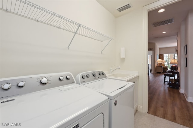 laundry room featuring washer and clothes dryer, wood-type flooring, and sink