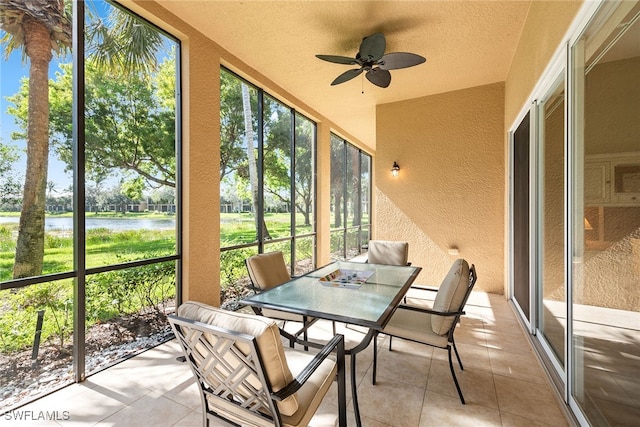 sunroom featuring ceiling fan and a water view