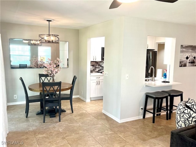 dining space featuring sink, ceiling fan with notable chandelier, and light tile patterned flooring