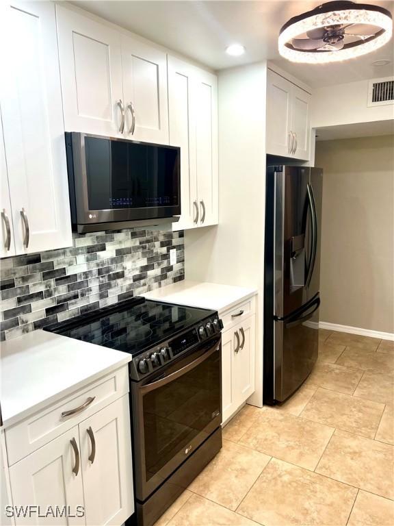 kitchen with range with electric cooktop, white cabinetry, stainless steel fridge, decorative backsplash, and light tile patterned floors