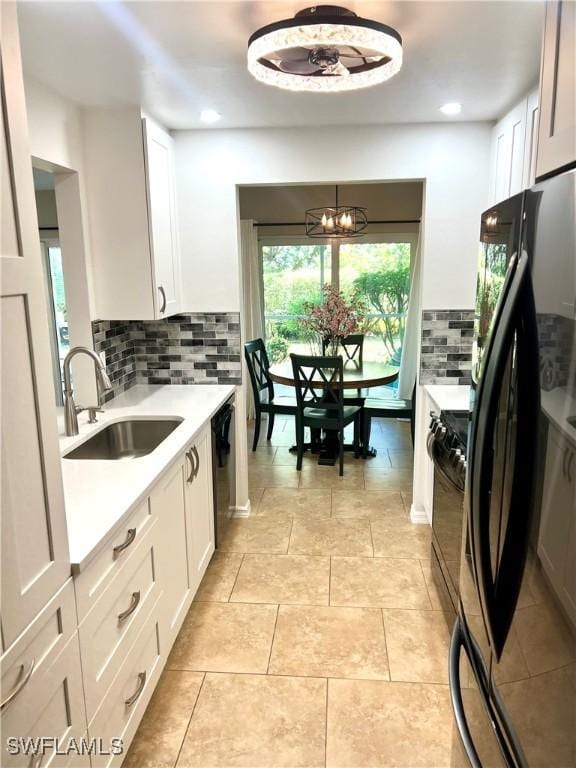 kitchen featuring sink, white cabinetry, black appliances, a chandelier, and backsplash