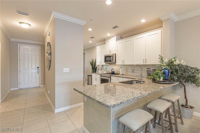 kitchen featuring kitchen peninsula, appliances with stainless steel finishes, light stone counters, sink, and white cabinetry