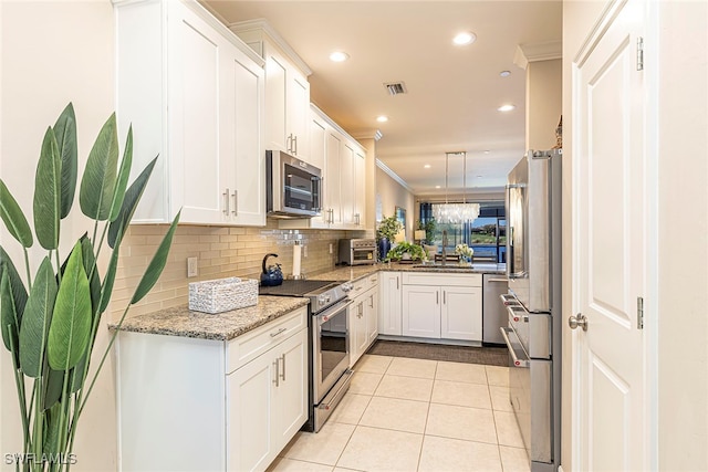 kitchen featuring white cabinetry, stainless steel appliances, light stone counters, light tile patterned floors, and ornamental molding