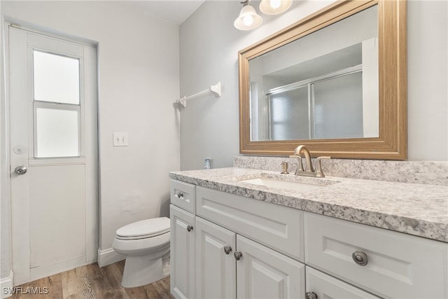 bathroom featuring toilet, vanity, wood-type flooring, and walk in shower