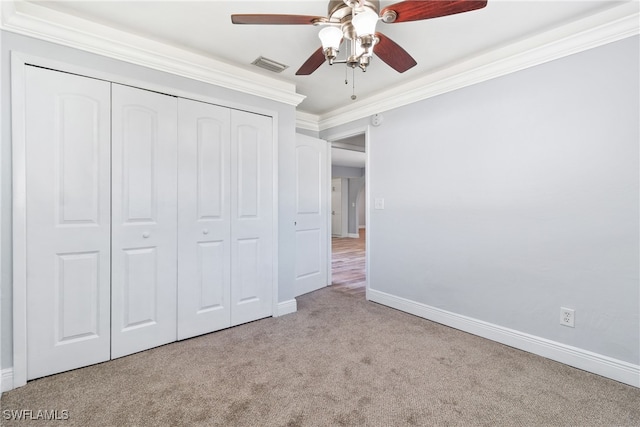 unfurnished bedroom featuring light carpet, a closet, ceiling fan, and crown molding