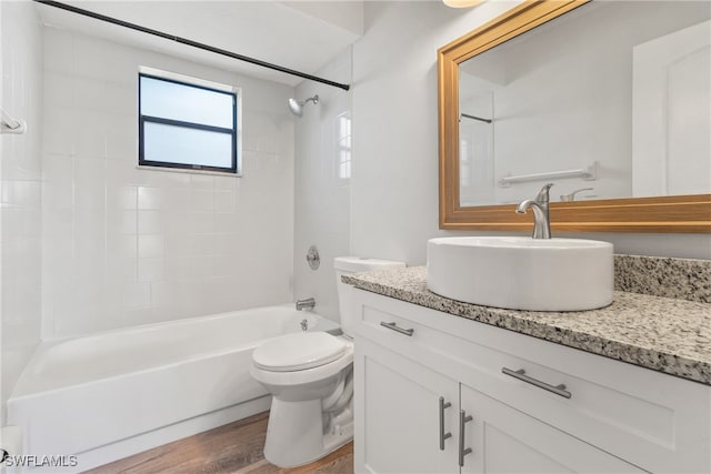 full bathroom featuring hardwood / wood-style flooring, vanity, toilet, and tiled shower / bath