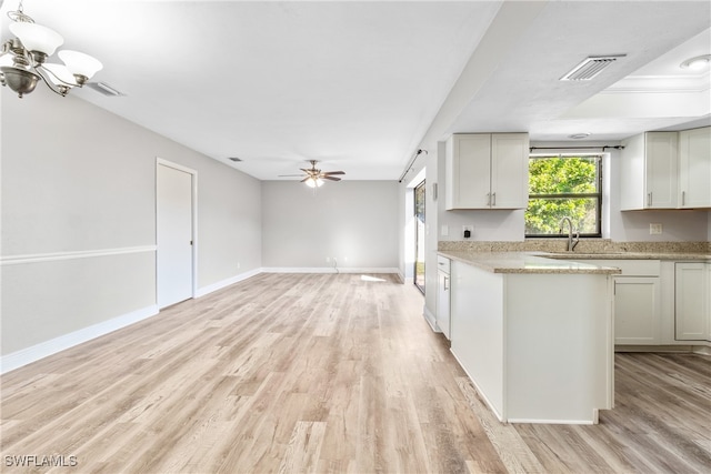 kitchen with light hardwood / wood-style flooring, white cabinets, ceiling fan with notable chandelier, and sink