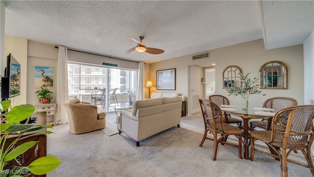 living room featuring ceiling fan, a textured ceiling, and light carpet