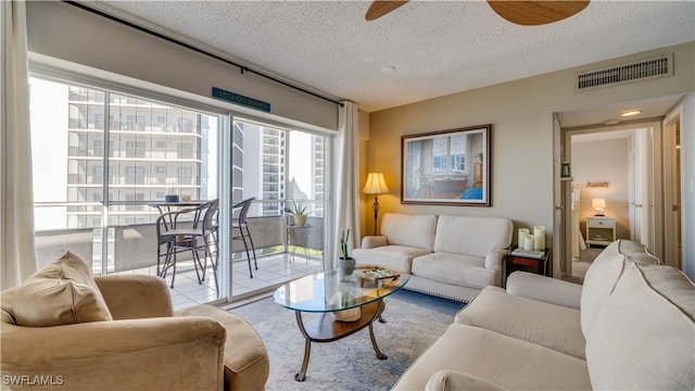 living area featuring ceiling fan, visible vents, and a textured ceiling