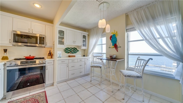 kitchen featuring white cabinets, appliances with stainless steel finishes, a water view, and a wealth of natural light