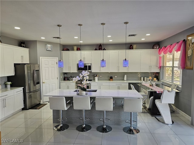 kitchen with hanging light fixtures, stainless steel appliances, backsplash, a breakfast bar area, and a kitchen island