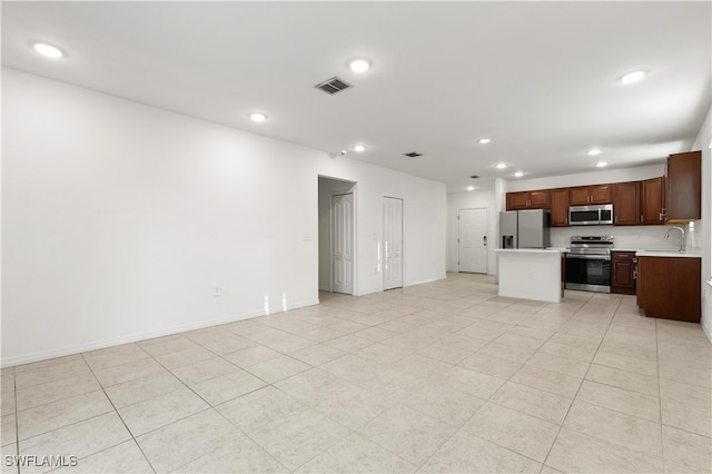 kitchen with a kitchen island, sink, light tile patterned floors, and stainless steel appliances