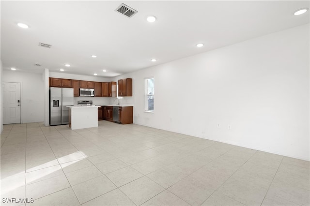 kitchen featuring a kitchen island, light tile patterned floors, and appliances with stainless steel finishes