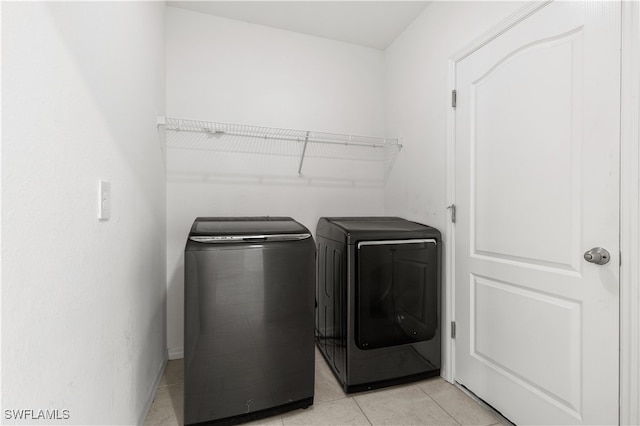 clothes washing area featuring washer and dryer and light tile patterned flooring