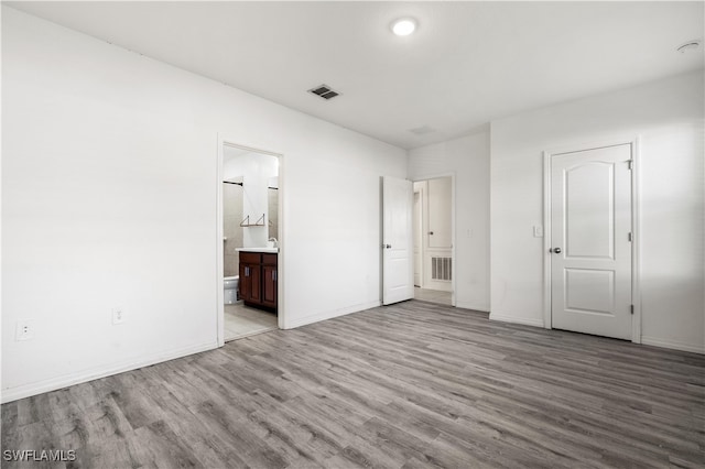 unfurnished bedroom featuring connected bathroom, light hardwood / wood-style floors, and a closet