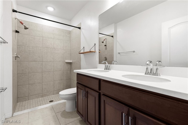 bathroom featuring toilet, a tile shower, vanity, and tile patterned floors