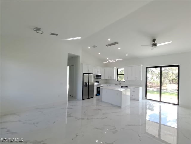 kitchen featuring appliances with stainless steel finishes, ceiling fan, a center island, white cabinetry, and lofted ceiling