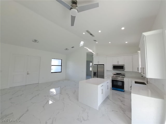 kitchen with stainless steel appliances, sink, a center island, white cabinetry, and lofted ceiling