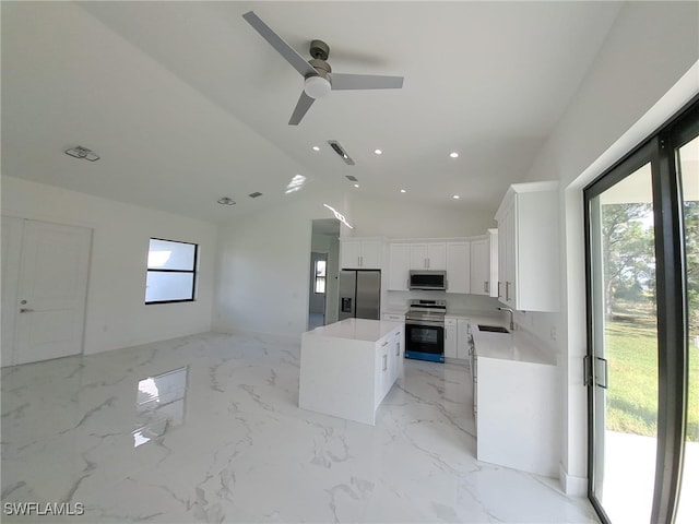 kitchen featuring appliances with stainless steel finishes, ceiling fan, a center island, white cabinetry, and lofted ceiling