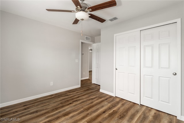 unfurnished bedroom with ceiling fan, dark wood-type flooring, and a closet